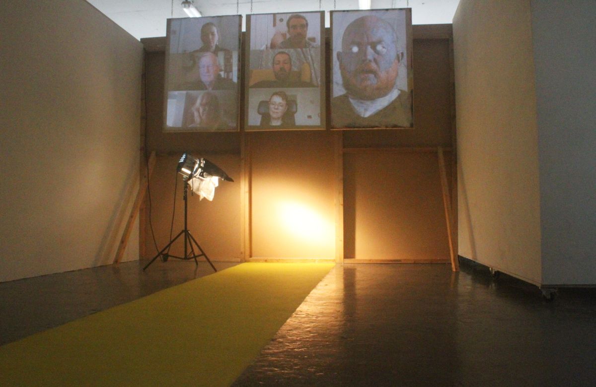 A movie light shines on the intersection between the yellow path and a possible door or entry point. There is a projection onto three frames that were Pop Art prints at one time in their past